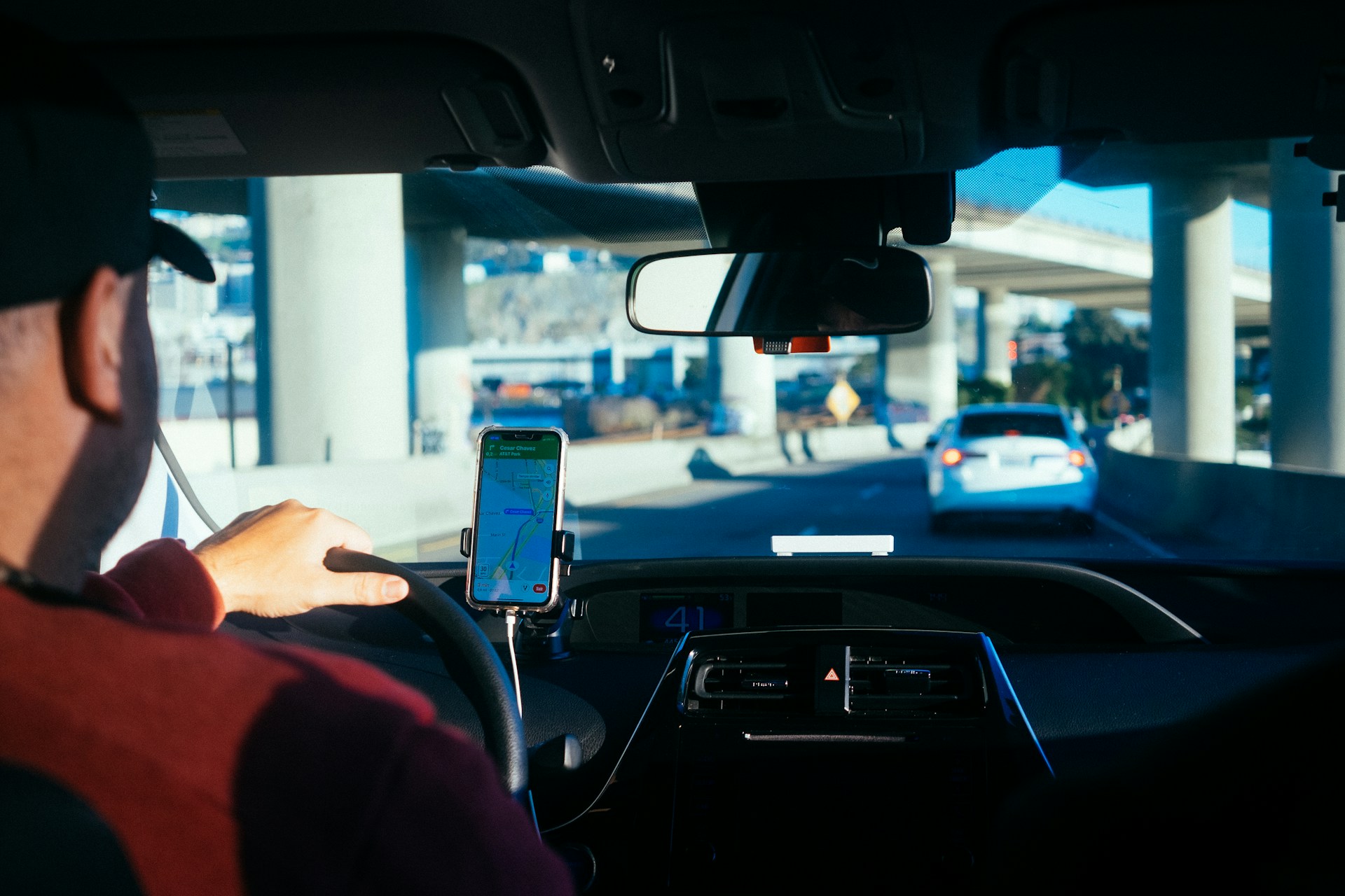 Chaufførvikar med GPS på mobilen, der kigger ud af frontruden